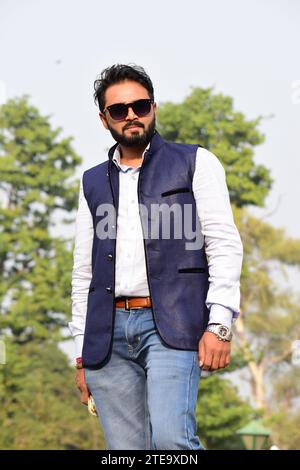 Tendance Young Indian Male pose en toute confiance avec des lunettes de soleil noires élégantes. Style de rue moderne, diversité ethnique, identité culturelle, beau modèle Banque D'Images