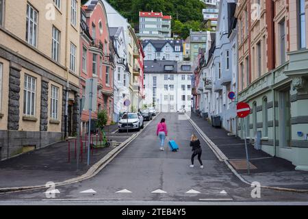 Bergen, Norvège, le 28 juin 2023 : deux femmes touristes prennent des photos avec une valise marchant le long de la rue vallonnée de la ville, Richard Nordraaks Gate, dans la descente Banque D'Images