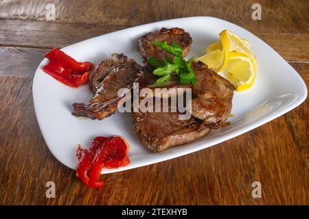 Côtelettes d'agneau avec poivrons rouges rôtis et citron dans un restaurant portugais. Banque D'Images