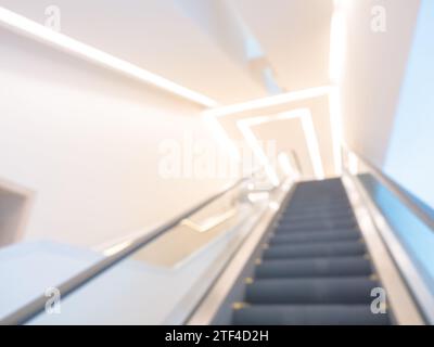 Scène photo floue d'escalator vide allant jusqu'à l'escalier supérieur avec décoration d'éclairage de plafond. Fond flou abstrait avec escalator en blanc clea Banque D'Images