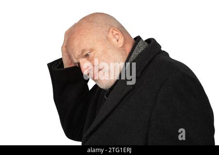 Homme mature frustré dans manteau d'hiver sombre exprimant des émotions bouleversées sur fond blanc Banque D'Images