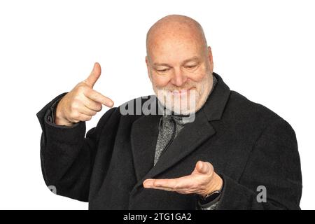 Heureux homme de 58 ans en manteau d'hiver pointant et examinant quelque chose Banque D'Images