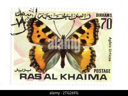 Un timbre-poste vintage de Ras Al Khaima représentant un papillon isolé sur fond blanc. Banque D'Images