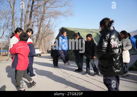 (231220) -- LINXIA, 20 déc. 2023 (Xinhua) -- des enfants jouent sur un site de relocalisation temporaire dans le village de Taojia, dans le comté de Jishan, dans la province du Gansu, au nord-ouest de la Chine, le 20 décembre 2023. Des opérations de sauvetage et de secours sont en cours dans un climat de froid intense alors qu'un tremblement de terre de magnitude 6,2 a tué 113 personnes et blessé 782 autres dans la province du Gansu, dans le nord-ouest de la Chine, selon une conférence de presse donnée mercredi. Au total, 87 076 personnes de 20 457 ménages ont été temporairement réinstallées dans des lieux sûrs. Les matériaux de secours d'urgence tels que les tentes, les couettes, les lits pliants et les tapis résistants à l'humidité ont été pressés Banque D'Images