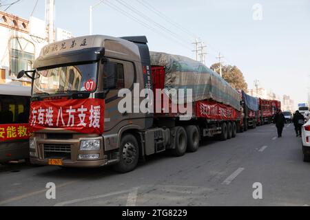 (231220) -- LINXIA, 20 déc. 2023 (Xinhua) -- des camions chargés de matériel de secours d'urgence sont vus à l'extérieur d'un site de relocalisation temporaire dans le village de Dahe, dans le comté de Jishan, dans la province du Gansu, au nord-ouest de la Chine, le 20 décembre 2023. Des opérations de sauvetage et de secours sont en cours dans un climat de froid intense alors qu'un tremblement de terre de magnitude 6,2 a tué 113 personnes et blessé 782 autres dans la province du Gansu, dans le nord-ouest de la Chine, selon une conférence de presse donnée mercredi. Au total, 87 076 personnes de 20 457 ménages ont été temporairement réinstallées dans des lieux sûrs. Matériel de secours d'urgence tels que tentes, courtepointes, pliage Banque D'Images