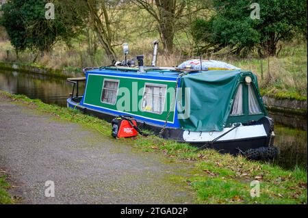 Petit bateau narrowboat chargeant ses batteries avec un générateur d'essence portable. Banque D'Images