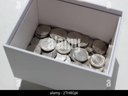 Boîte blanche avec des pièces d'argent ukrainiennes sur la surface blanche photo stock Banque D'Images
