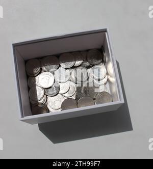 Photo carrée de boîte d'argent en carton avec des pièces ukrainiennes dispersées avec dénomination différente Banque D'Images