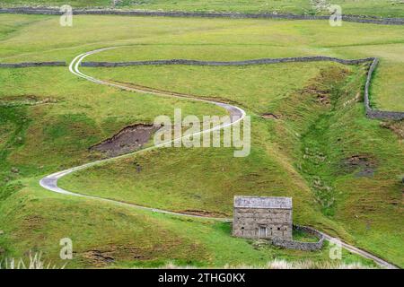 Route zigzag dans un champ dans Yorkshire Dales Angleterre avec une maison en pierre Banque D'Images