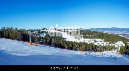 Pistes de ski, télésièges, skieurs et snowboarders dans la station de ski Bialka Tatrzanska en Pologne en hiver. Panorama aérien en basse lumière de décembre avec bleu s Banque D'Images