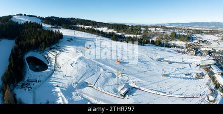 Piste de ski, télésièges, skieurs et snowboarders à Bialka Tatrzanska station de ski en Pologne sur la montagne Kotelnica en hiver. Panorama aérien en bas Decem Banque D'Images