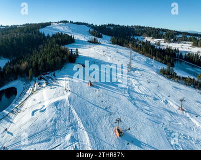 Piste de ski, télésièges, skieurs et snowboarders à Bialka Tatrzanska station de ski en Pologne sur la montagne Kotelnica en hiver. Vue aérienne en bas décembre Banque D'Images