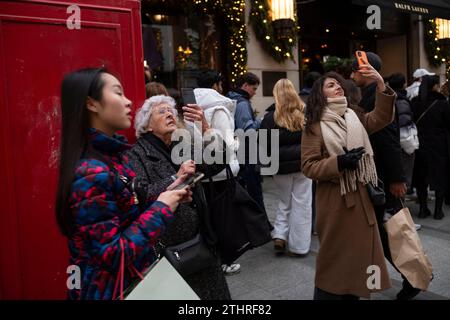 Touristes festifs en force prenant des selfies et des photos d'expositions de Noël le long de Old Bond Street au cœur de Mayfair à Londres, le 20 décembre 2023. Banque D'Images