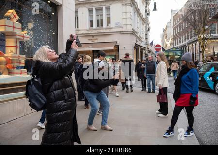 Touristes festifs en force prenant des selfies et des photos d'expositions de Noël le long de Old Bond Street au cœur de Mayfair à Londres, le 20 décembre 2023. Banque D'Images