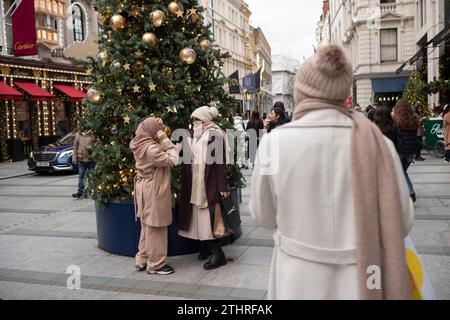 Touristes festifs en force prenant des selfies et des photos d'expositions de Noël le long de Old Bond Street au cœur de Mayfair à Londres, le 20 décembre 2023. Banque D'Images