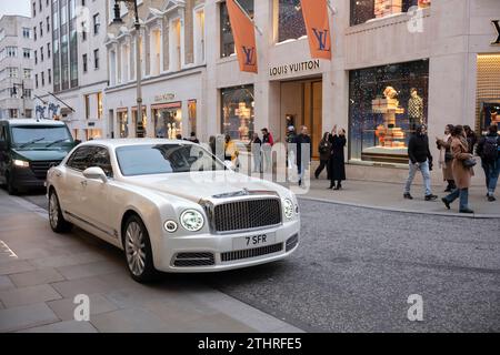 Des touristes festifs en force prennent des selfies et des photos d'expositions de Noël et de voitures de luxe le long d'Old Bond Street, au cœur de Mayfair, à Londres, en Angleterre Banque D'Images