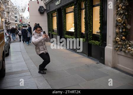 Touristes festifs en force prenant des selfies et des photos d'expositions de Noël le long de Old Bond Street au cœur de Mayfair à Londres, le 20 décembre 2023. Banque D'Images