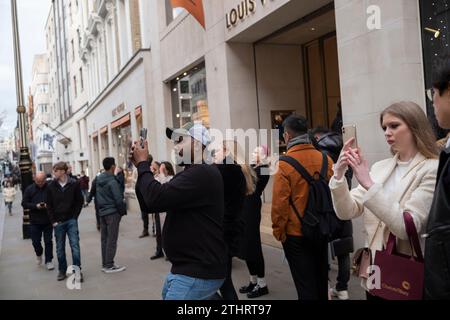 Touristes festifs en force prenant des selfies et des photos d'expositions de Noël le long de Old Bond Street au cœur de Mayfair à Londres, le 20 décembre 2023. Banque D'Images