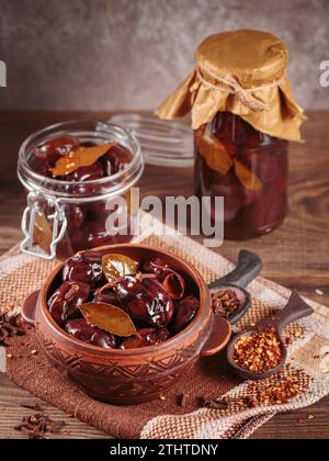 Prunes marinées aux épices dans un pot en verre sur la table de cuisine Banque D'Images