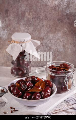 Prunes marinées aux épices dans un pot en verre sur la table de cuisine Banque D'Images