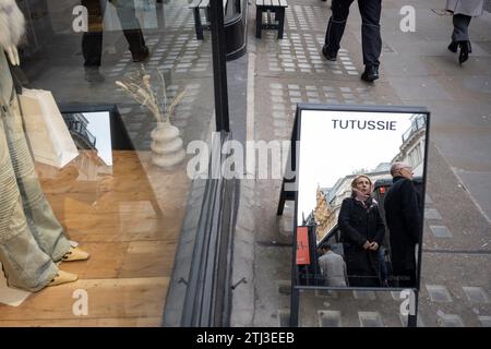 Les acheteurs de Noël dans un miroir de rue devant le détaillant Tutussie à Mayfair, le 20 décembre 2023, à Londres, Angleterre. Tutussie a commencé à l'origine comme une marque de vêtements d'extérieur en cachemire, s'étendant dans d'autres catégories, tout en gardant toujours la slow fashion et la durabilité. Banque D'Images