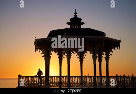 Silhouette du kiosque victorien de Brighton avec un homme solitaire au coucher du soleil. Brighton & Hove, Sussex de l'est, Angleterre. Ciel bleu et doré. Banque D'Images