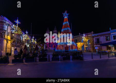 Un spectacle laser projette des motifs colorés sur la façade de l'église paroissiale de Notre-Dame de Pompéi à Marsaxlokk, à Malte, à côté d'une pyramide de Noël illuminée ; les places de Malte sont baignées de lumière colorée dans les semaines précédant Noël. Construite à partir de 1890 pour la communauté de pêcheurs en pleine expansion et érigée en paroisse indépendante depuis 1897, l'église a reçu sa façade ouest baroque à la fin des années 1920 sous l'architecte Giuseppe Lia. Banque D'Images