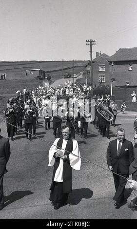 Années 1960, historique, prêtre menant une procession de personnes et fanfare de la Moorside Methodist Church & Sunday School, Oldham, Angleterre, Royaume-Uni. Fondée en 1884, l'église faisait partie du mouvement méthodiste dérivé de la vie et des enseignements de John Wesley et est devenue populaire dans le nord industrialisé de l'Angleterre. Banque D'Images