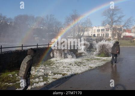 Paterson, New Jersey, États-Unis. 20 décembre 2023. Les enfants courent à travers un arc-en-ciel au parc Mary Ellen Kramer adjacent au parc historique national de Great Falls à Paterson, dans le New Jersey. Paterson ainsi que Little Falls et d'autres communautés du New Jersey le long de la rivière Passiac ont subi des inondations dévastatrices qui ont été déclenchées par une forte chute de pluie côtière qui a frappé le New Jersey dimanche et lundi (image de crédit : © Brian Branch Price/ZUMA Press Wire) À USAGE ÉDITORIAL SEULEMENT! Non destiné à UN USAGE commercial ! Banque D'Images