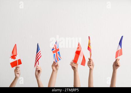 Mains féminines avec des drapeaux de différents pays sur fond clair Banque D'Images