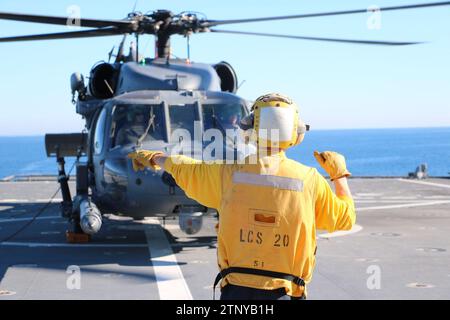 Le Mineman de 3rd Class Ethan Crawford, originaire d'Edmore, Michigan, affecté à bord du navire de combat côtier USS Cincinnati (LCS 20), dirige un hélicoptère HH-60G Pave Hawk de la Force aérienne affecté au 305th Rescue Squadron, 943d Rescue Group, 920th Rescue Wing, alors qu’il atterrit sur le pont d’envol du navire à l’appui de l’exercice Steel Knight 23.2, 5 décembre 2023. Steel Knight est un exercice en trois phases conçu pour former la I Marine Expeditionary Force à la planification, au déploiement et au commandement et au contrôle d'une force conjointe contre une force de combat adversaire pair ou quasi pair et améliorer le live-f existant Banque D'Images