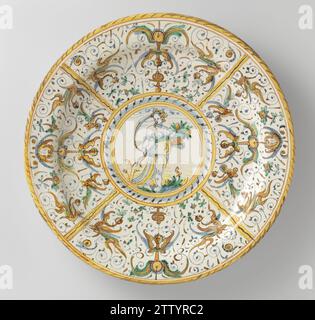 Plat avec Pomona, Anonyme, c. 1580 - c. 1640 plat rond de majolique peinte multicolore. Au milieu se trouve un cercle peint dans lequel une femme debout (Pomona) sur un sol avec un panier avec des fleurs dans la main gauche (?). Le bord est divisé par quatre lignes en quatre cours dans lesquels des feuilles fines et des animaux sont peints (décor Patanazzi). Faïence Urbino. glaçure d'étain. Majolica glacé au plomb plat rond en majolica peint multicolore. Au milieu se trouve un cercle peint dans lequel une femme debout (Pomona) sur un sol avec un panier avec des fleurs dans la main gauche (?). Le bord est divisé par fo Banque D'Images