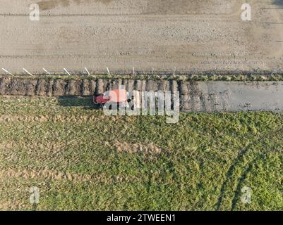 Tracteur cultivant la terre avec un timon rotatif pour préparer la terre pour la prochaine plantation de riz Banque D'Images