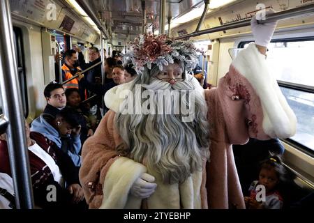 Mexico, Mexique. 20 décembre 2023. L'artiste scénique spécialisé dans le statuisme, JOSE MIGUEL MOCTEZUMA, caractérisé comme le Père Noël illuminé, monte dans le métro entre distribuer des câlins et prendre des photos souvenirs avec les utilisateurs du système de transport collectif Metro à Mexico. (Image de crédit : © Luis Barron/eyepix via ZUMA Press Wire) USAGE ÉDITORIAL SEULEMENT! Non destiné à UN USAGE commercial ! Banque D'Images