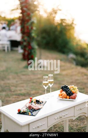 Table avec deux verres de champagne et assiettes de friandises festives se tient dans une clairière Banque D'Images