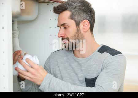 homme ayant une inspection sous l'évier de cuisine Banque D'Images