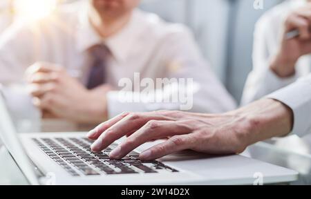 Vue en gros plan de deux jeunes collègues travaillant sur un ordinateur portable au bureau Banque D'Images