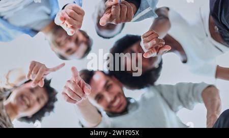 Gros plan portrait, vue de dessous, visages heureux des différents employés de l'équipe debout dans le cercle Banque D'Images