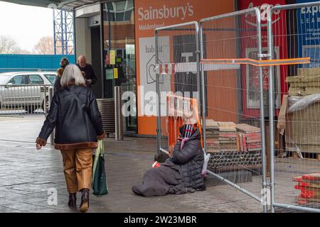 Maidenhead, Berkshire, Royaume-Uni. 15 décembre 2023. Une femme supplie devant un supermarché Sainsbury's à Maidenhead, Berkshire. Sainsbury's offre des prix moins chers sur la nourriture et les boissons aux clients qui détiennent une carte Nectar. Le supermarché Rival Tesco fait également de même avec leurs Clubcards dans le but de fidéliser la clientèle. Crédit : Maureen McLean/Alamy Banque D'Images