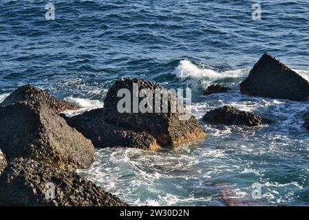 Coastal Serenity : des roches marines résistantes à l'étreinte douce des petites vagues le long du rivage. Banque D'Images