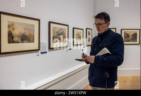 Édimbourg, Royaume-Uni. 21 décembre 2023 photo : artiste local, Mark Kirkham, également connu sous le nom de Edinburgh Sketcher, créant ses propres impressions de l'exposition. L’exposition annuelle très attendue des aquarelles de J.M.W. Turner par les National Galleries of Scotland a lieu entre janvier 1 2024 et janvier 31 2024. Près de 40 œuvres seront exposées, dont des paysages spectaculaires de l’Himalaya, des Alpes suisses et de l’île de Skye. Voyageant à travers la Grande-Bretagne, l'Europe et au-delà, cette exposition fascinante capture la vie et la carrière de cet artiste bien-aimé. Crédit : Rich Dyson/Alamy Banque D'Images