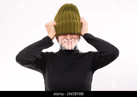 Adolescente moderne en bonnet beanie tricoté oversize et pull foncé. Jeune femme à la mode posant. Portrait de studio Banque D'Images