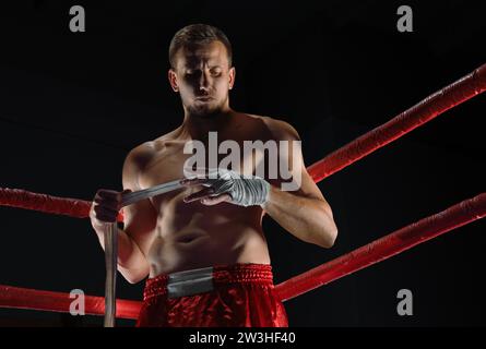 Sportif professionnel des arts martiaux mixtes se tient après le combat gagné près du sac et regarde de manière menaçante son prochain adversaire Banque D'Images