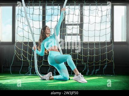 Belle gymnaste fille se réchauffant dans la salle d'athlétisme. Exercices avec cordes. Concept de fitness. Supports mixtes Banque D'Images