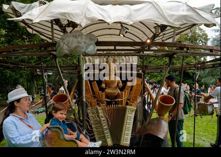 Carrousel pittoresque à moteur manuel pendant le festival de la fête de la Suisse, avec des parents poussant leurs enfants sur des chaises oscillantes, autour d'un garçon batteur en bois. Banque D'Images