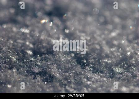 Cristaux de neige brillants, flocons de neige dans un plan macro avec une profondeur de champ minimale, dans certains cristaux de neige la lumière réfracte en couleurs arc-en-ciel, lumière Banque D'Images