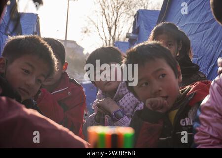 (231221) -- LINXIA, 21 déc. 2023 (Xinhua) -- des enfants écoutent un expert en santé mentale d'une équipe de conseil psychologique dans un site de relocalisation temporaire dans le village de Yangwa, dans le comté de Jishan, dans la province du Gansu, au nord-ouest de la Chine, le 21 décembre 2023. Après le tremblement de terre de magnitude 6,2 dans la province du Gansu, dans le nord-ouest de la Chine, un total de 28 experts nationaux et provinciaux en santé mentale se sont précipités à Gansu pour offrir des conseils psychologiques aux patients hospitalisés et à leurs compagnons, aux familles des victimes et aux personnes touchées par le tremblement de terre, y compris les travailleurs humanitaires. Gansu est Worki Banque D'Images