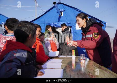 (231221) -- LINXIA, 21 déc. 2023 (Xinhua) -- Un expert en santé mentale d'une équipe de conseil psychologique aide des enfants à soulager le stress en peignant sur un site de relocalisation temporaire dans le village de Yangwa du comté de Jishan, dans la province du Gansu, au nord-ouest de la Chine, le 21 décembre 2023. Après le tremblement de terre de magnitude 6,2 dans la province du Gansu, dans le nord-ouest de la Chine, un total de 28 experts nationaux et provinciaux en santé mentale se sont précipités à Gansu pour offrir des conseils psychologiques aux patients hospitalisés et à leurs compagnons, aux familles des victimes et aux personnes touchées par le tremblement de terre, y compris la catastrophe Banque D'Images