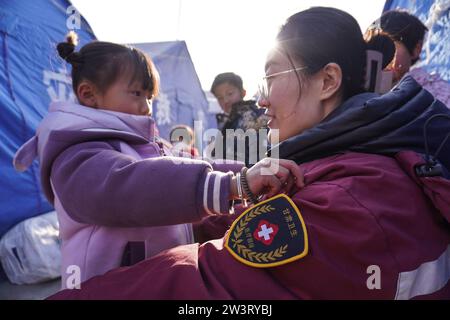 (231221) -- LINXIA, 21 déc. 2023 (Xinhua) -- Un expert en santé mentale d'une équipe de conseil psychologique joue un jeu avec un enfant sur un site de relocalisation temporaire dans le village de Yangwa, dans le comté de Jishan, dans la province du Gansu, au nord-ouest de la Chine, le 21 décembre 2023. Après le tremblement de terre de magnitude 6,2 dans la province du Gansu, dans le nord-ouest de la Chine, un total de 28 experts nationaux et provinciaux en santé mentale se sont précipités à Gansu pour offrir des conseils psychologiques aux patients hospitalisés et à leurs compagnons, aux familles des victimes et aux personnes touchées par le tremblement de terre, y compris les travailleurs humanitaires. Gansu i. Banque D'Images