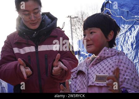 (231221) -- LINXIA, 21 déc. 2023 (Xinhua) -- Un expert en santé mentale d'une équipe de conseil psychologique joue un jeu avec un enfant sur un site de relocalisation temporaire dans le village de Yangwa, dans le comté de Jishan, dans la province du Gansu, au nord-ouest de la Chine, le 21 décembre 2023. Après le tremblement de terre de magnitude 6,2 dans la province du Gansu, dans le nord-ouest de la Chine, un total de 28 experts nationaux et provinciaux en santé mentale se sont précipités à Gansu pour offrir des conseils psychologiques aux patients hospitalisés et à leurs compagnons, aux familles des victimes et aux personnes touchées par le tremblement de terre, y compris les travailleurs humanitaires. Gansu i. Banque D'Images